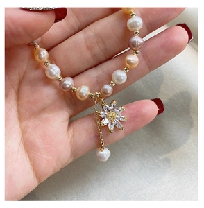 Macro shot of colorful freshwater pearls and sunflower crystal pendant on a gold bracelet