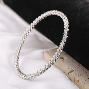 Minimalist 5mm stainless steel beaded bangle bracelet with spiral texture on stone background