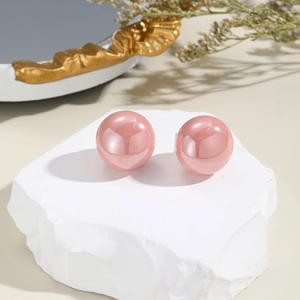 Close-up of elegant pink pearl earrings set on a textured white stone with golden decor