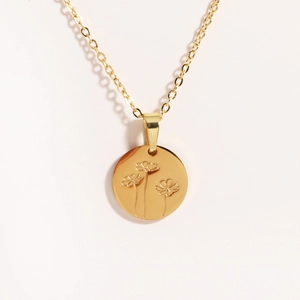Close-up of golden stainless steel oval pendant with delicate engraved floral patterns