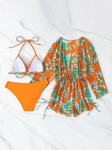Flat lay of tropical orange three-piece bikini set with palm leaf cover-up on marble
