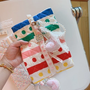 Détail de la pochette matelassée fleurie avec pois arc-en-ciel, dentelle et perles