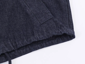 Detailaufnahme der dunkelblauen Denim-Nähte und des Kordelzugs der modischen Jacke