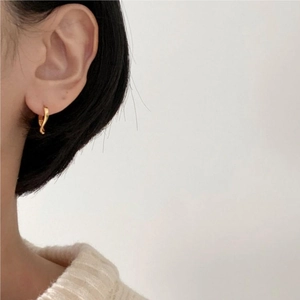 Close-up of a twisted gold hoop earring worn by a model for a stylish minimalist look