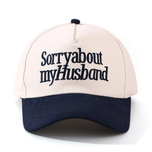 Detail der Sorry about my husband Stickerei auf der blau-weißen Trucker-Mütze