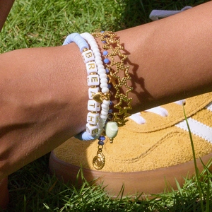Gros plan de bracelets superposés en perles d'argile bleue et breloques étoile dorées
