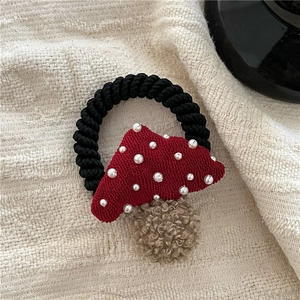 Close-up of a red fabric mushroom hair tie with white pearls and a black elastic band