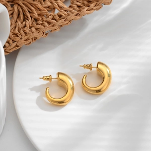 French vintage thick C-shaped gold-plated hoop earrings with polished finish on a minimalist mat