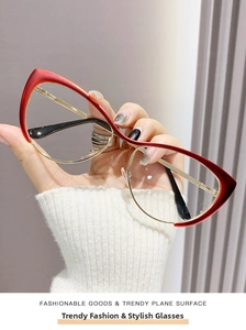 Detail of red and gold cat-eye glasses held in hand showing the metal frame and temple tips
