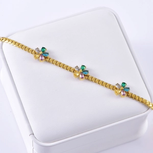 Gold bracelet with colorful zircon flower pendants on a white jewelry display box