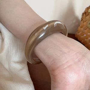 Macro shot of thick acrylic cuff bracelet with brown marble texture and glossy finish