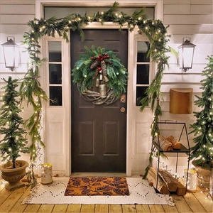 Christmas wreath with green pine needles, red berries, pine cones and rustic metal bells