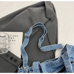 Detail of light blue denim tote with silver adjustable metal buckle and zipper closure