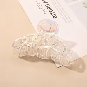 Macro shot of iridescent chain-link hair claw clip with colorful aurora finish on a magazine