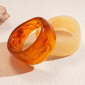 Close-up of thick resin bangles in amber tortoiseshell and translucent cream colors