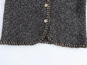 Detail of herringbone wool fabric with metallic crest buttons and braided gold trim