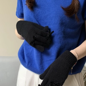 Close-up of black knitted gloves featuring a delicate bow detail and warm winter texture