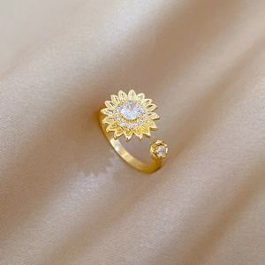 Close-up of a gold sunflower ring with sparkling crystals on champagne silk background