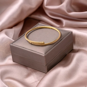 Detail of gold cable twist open cuff bracelet with spherical end caps on silk backdrop