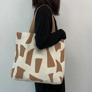 Canvas tote bag with brown geometric patterns and bear logo shown on a model's shoulder