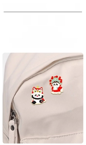 Macro view of Chinese style panda enamel pins attached to a beige canvas bag fabric