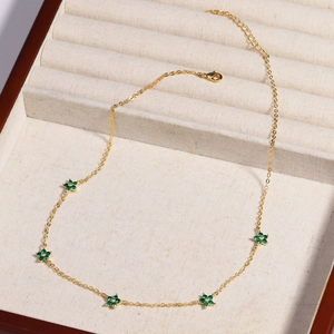 Detail view of a gold chain necklace with green gem flowers in a velvet jewelry box