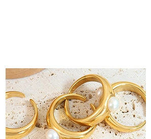 Detailed view of four adjustable gold-plated rings with white pearls on a textured stone surface