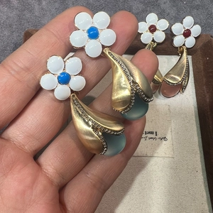Détail de boucles d'oreilles vintage en résine avec fleurs en émail et pierres colorées
