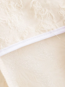 Dettaglio macro del tessuto jacquard beige con frange e cuciture con bordino bianco