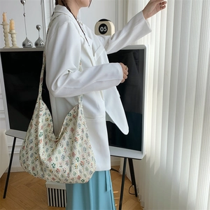Close-up of a floral large-capacity canvas tote bag worn by a model in a white blazer
