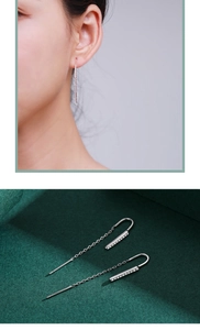 Detail of s925 silver long chain earrings with sparkling zircon bar on green velvet