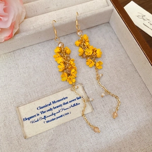 Detail of long yellow floral tassel earrings with gold chains on a jewelry tray