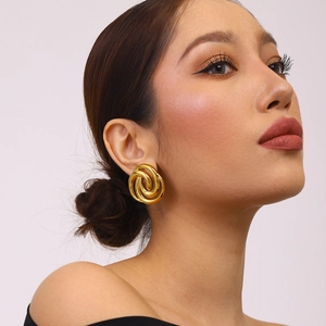 Detailed view of model wearing golden 18k plated titanium steel spiral knot earrings
