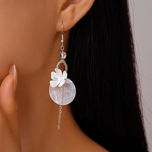 Macro detail of long tassel earrings with white flower and pearlescent shell disk