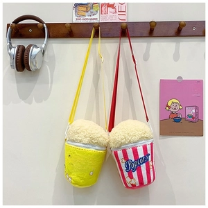Deux adorables sacs peluche en forme de popcorn suspendus à un porte-manteau en bois.