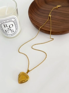Gros plan détaillé d'un collier médaillon cœur doré avec gravure florale vintage
