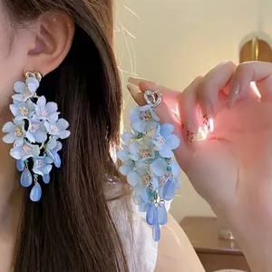 Detailed close-up of blue multi-layer flower earrings with heart studs and bead drops