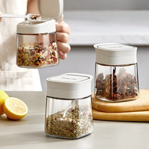 Three-piece glass spice jar set with white lids in a modern kitchen setting