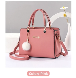 Close-up of dusty pink handbag with golden logo, heart chain and soft fur ball accessory