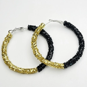 Detail view of large hoop earrings in gold and black glitter finishes with sequins