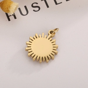 Golden stainless steel sun pendant with micro-pave zircon on artistic paper background