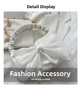 Close-up of white crossbody bag with organza bow, scrunchie handle and gold chain
