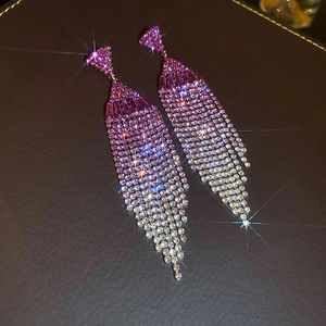 Detail of tassel earrings with gradient pink rhinestones and silver fringe on dark leather