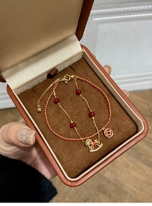 Detail of 18k gold plated double-layer bracelet with horse charm and red beads in gift box