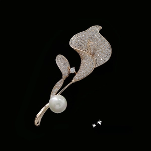 Detailed view of calla lily crystal brooch with a large white pearl and gold finish