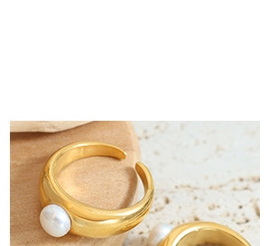 Macro shot of an adjustable gold ring featuring a single pearl on a textured stone surface