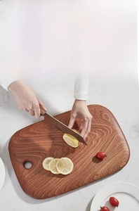 Close-up of rectangular ebony wood cutting board with round handle hole and natural wood grain