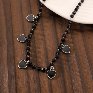 Detail of gothic black beaded necklace featuring five heart pendants with silver frames