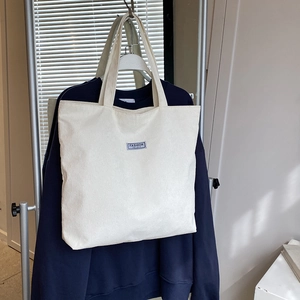 Close-up of beige corduroy tote bag featuring ribbed texture and Fashion Instinct label