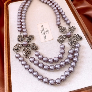 Detail of double-layer lavender pearl necklace with rhinestone flower accents on wood tray